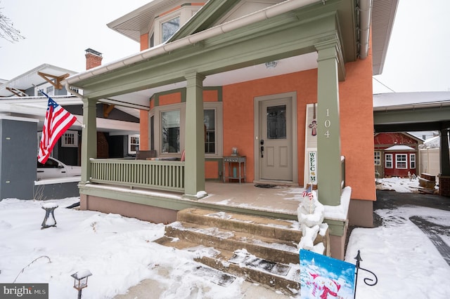 snow covered property entrance with a porch