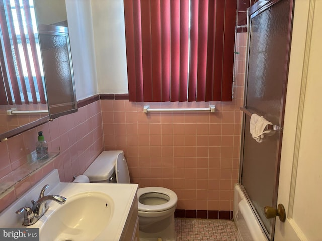 full bathroom with shower / bath combination with glass door, tile patterned flooring, tile walls, vanity, and toilet