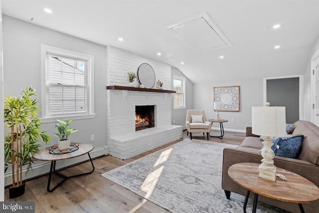 living room featuring hardwood / wood-style flooring, vaulted ceiling, plenty of natural light, and a brick fireplace