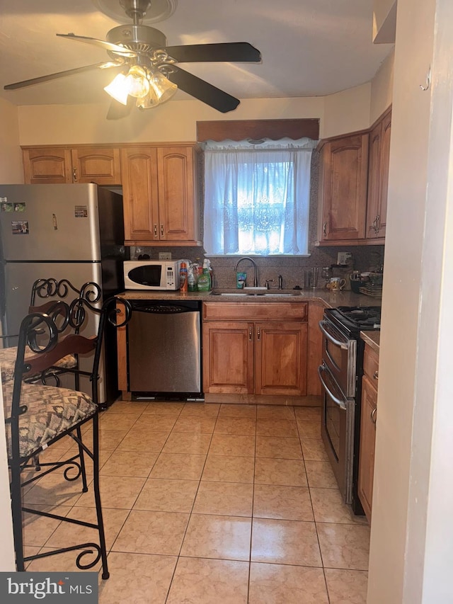 kitchen with sink, backsplash, light tile patterned floors, ceiling fan, and stainless steel appliances