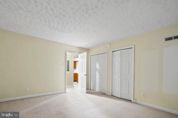 unfurnished bedroom with two closets and a textured ceiling