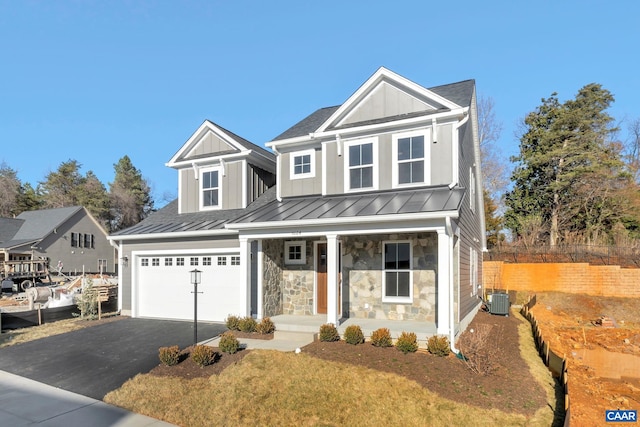 view of front of home featuring a garage, cooling unit, covered porch, and a front lawn