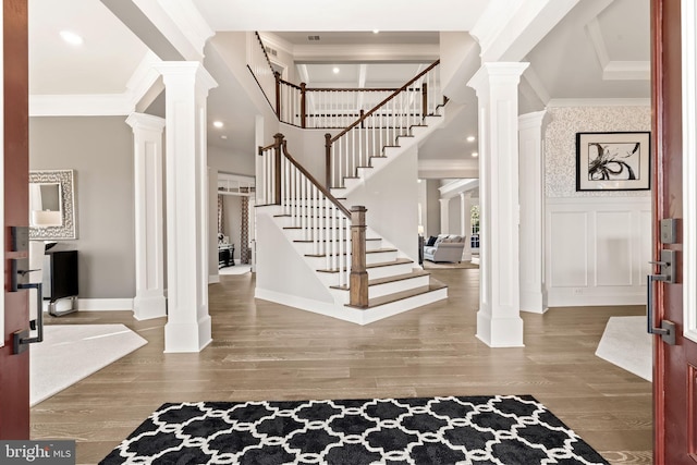 entryway featuring a high ceiling, crown molding, decorative columns, and hardwood / wood-style floors