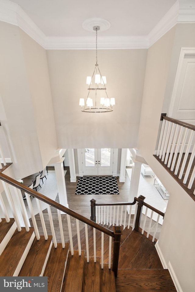 stairway featuring hardwood / wood-style floors, a chandelier, and crown molding