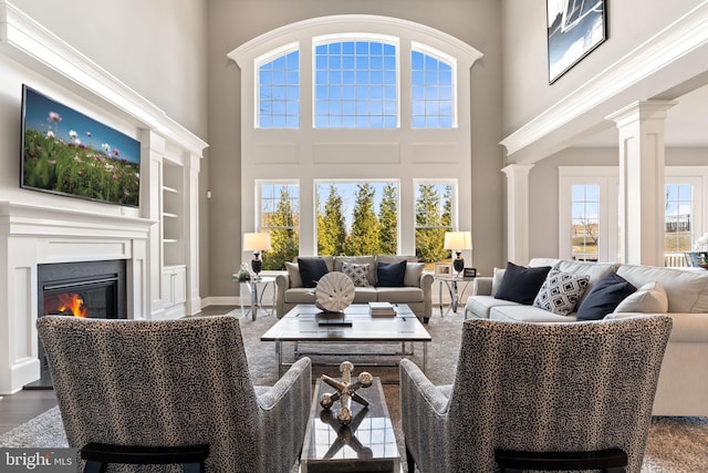 living room featuring decorative columns, a towering ceiling, and hardwood / wood-style floors