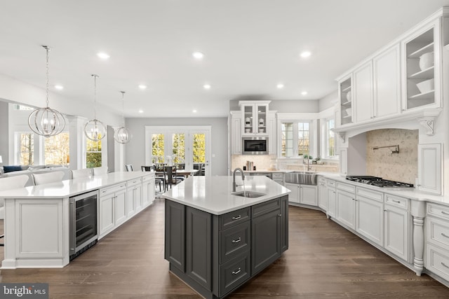 kitchen with sink, a center island with sink, beverage cooler, and white cabinetry