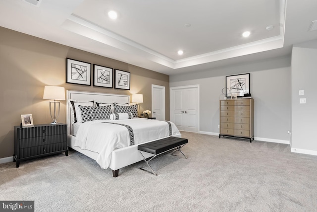 carpeted bedroom featuring a tray ceiling, ornamental molding, and a closet