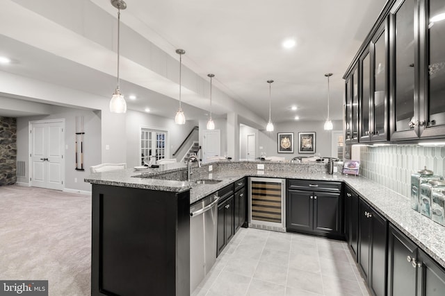 kitchen featuring kitchen peninsula, beverage cooler, light stone counters, and decorative light fixtures