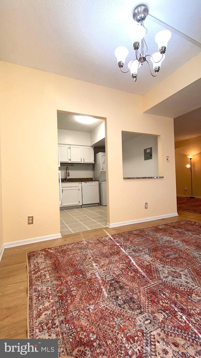 unfurnished living room featuring an inviting chandelier, sink, hardwood / wood-style flooring, and a textured ceiling