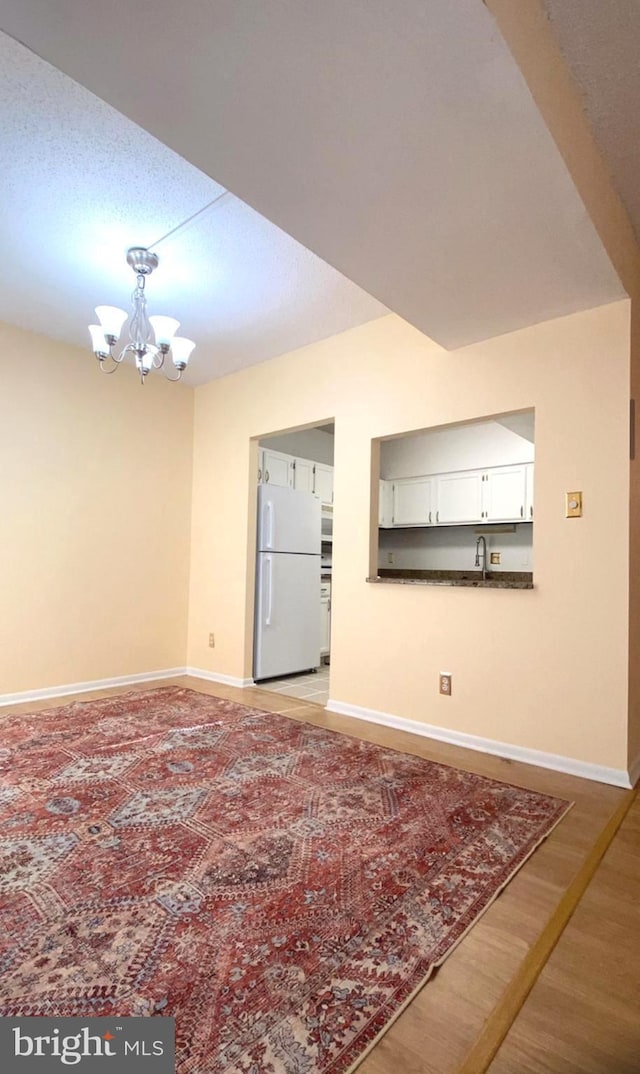 interior space featuring an inviting chandelier, sink, and light wood-type flooring