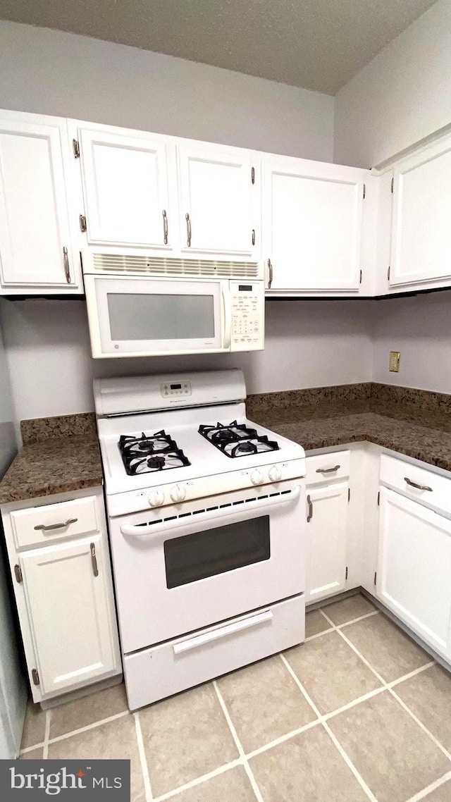 kitchen with white cabinetry, white appliances, and light tile patterned floors