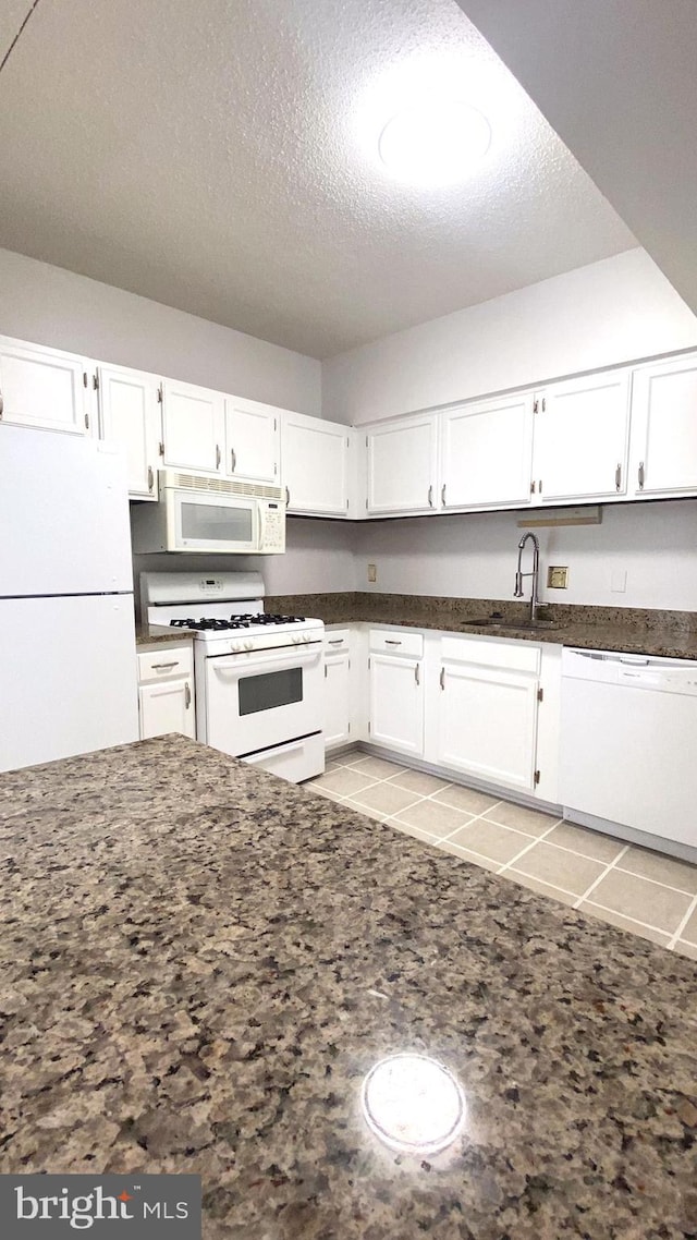 kitchen with white appliances, sink, a textured ceiling, and white cabinets