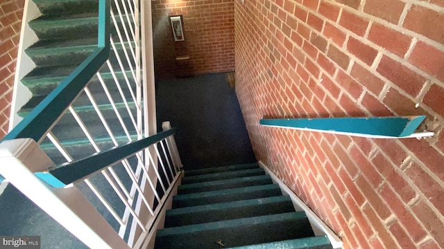 staircase featuring brick wall