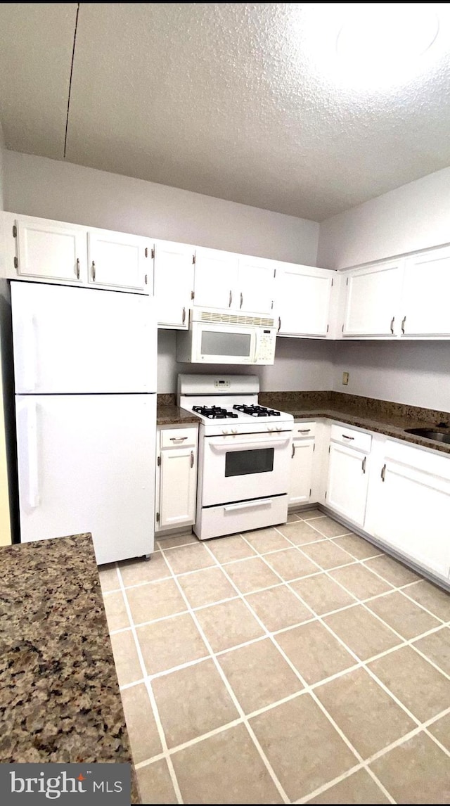 kitchen featuring white cabinetry, light tile patterned floors, and white appliances