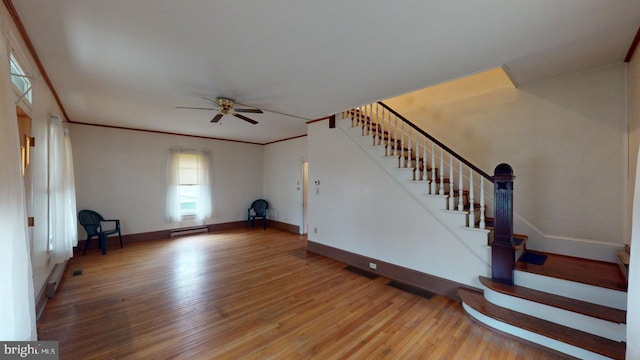 unfurnished living room with hardwood / wood-style flooring, crown molding, ceiling fan, and baseboard heating