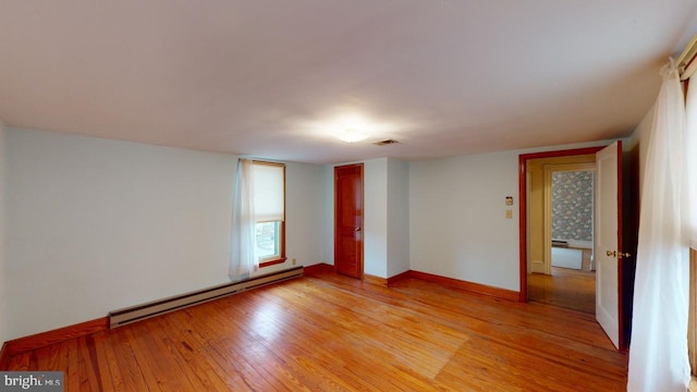 unfurnished room with light hardwood / wood-style floors and a baseboard heating unit