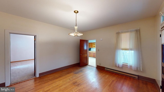 unfurnished room featuring a baseboard radiator and light hardwood / wood-style flooring