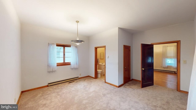 unfurnished bedroom featuring baseboard heating, light colored carpet, and connected bathroom