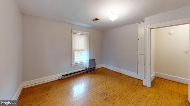 unfurnished room featuring a baseboard radiator and light hardwood / wood-style flooring