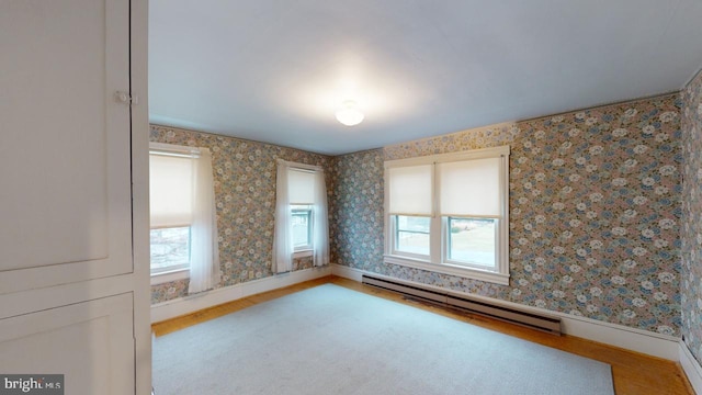 spare room featuring wood-type flooring, a baseboard heating unit, and a wealth of natural light