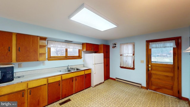 kitchen featuring white fridge, a baseboard heating unit, and sink