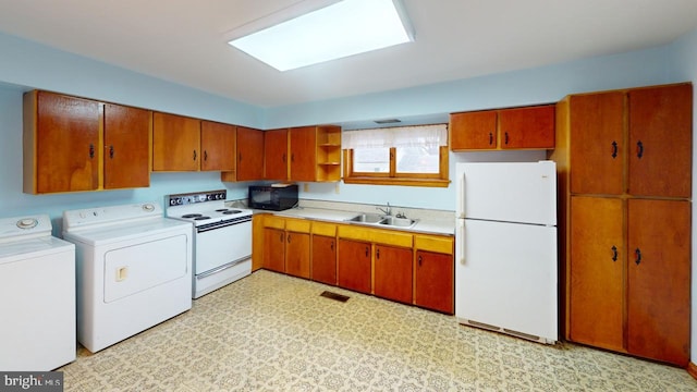 kitchen with washing machine and dryer, sink, and white appliances