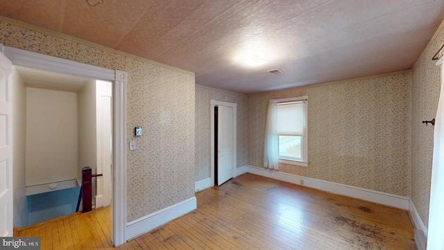 unfurnished bedroom with wood-type flooring, ornamental molding, and a closet