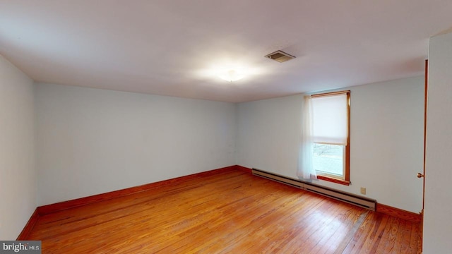 unfurnished room featuring a baseboard heating unit and light hardwood / wood-style flooring