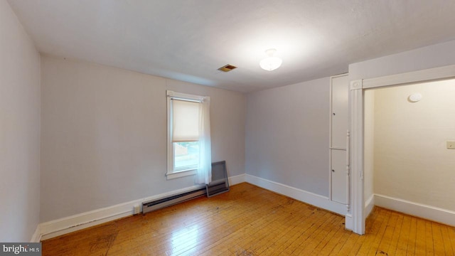 empty room featuring a baseboard radiator and light wood-type flooring