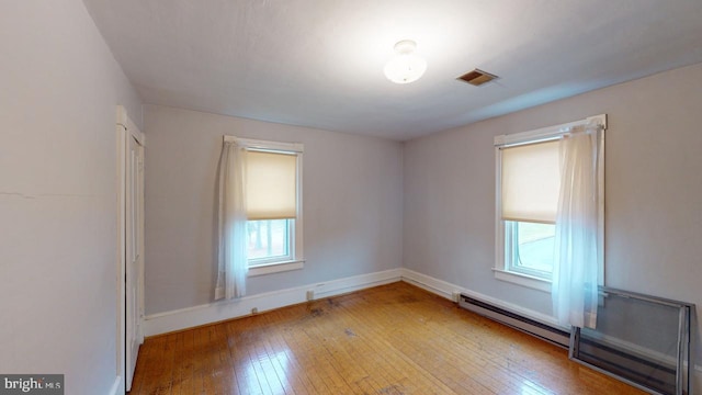 empty room featuring a baseboard radiator and light wood-type flooring