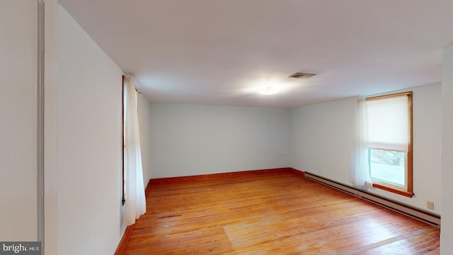 unfurnished room with a baseboard heating unit and light hardwood / wood-style floors