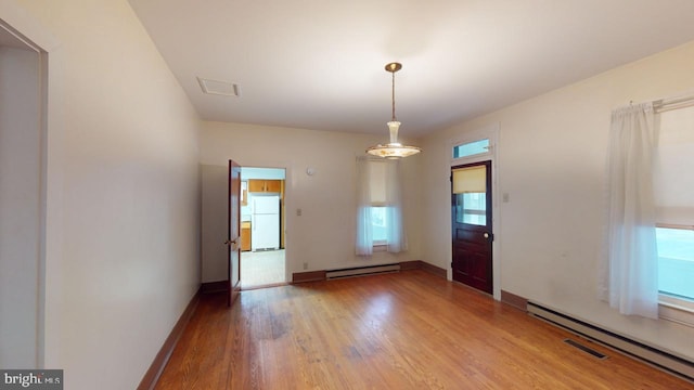 spare room featuring baseboard heating and light wood-type flooring