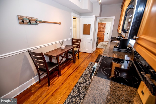 kitchen with electric range, light hardwood / wood-style floors, and dark stone counters