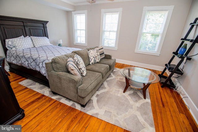 bedroom featuring multiple windows, wood-type flooring, and ornamental molding