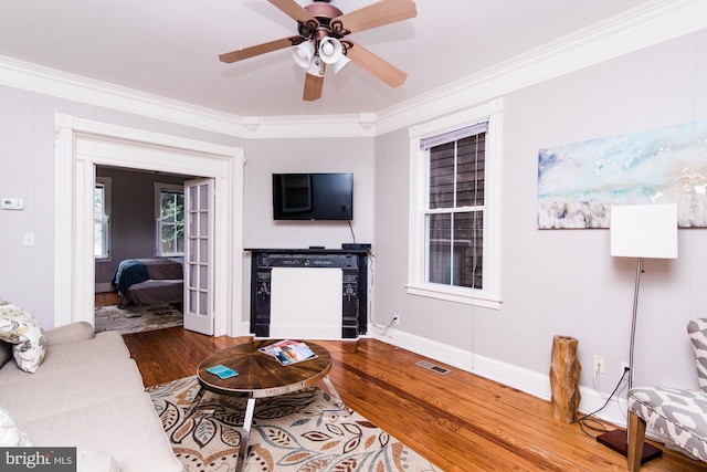 living room featuring hardwood / wood-style flooring, crown molding, and ceiling fan