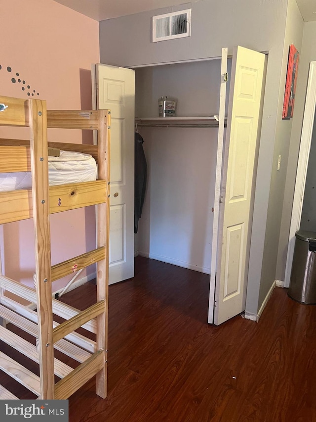 bedroom with dark wood-type flooring and a closet