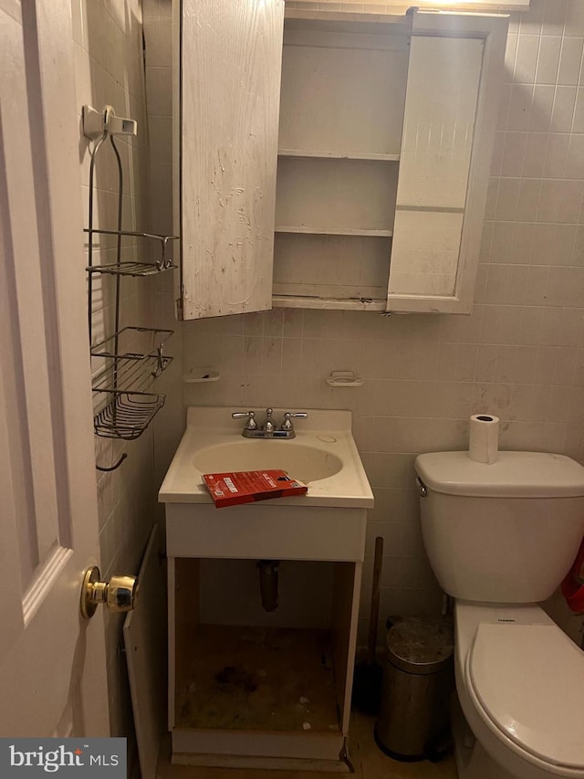 bathroom featuring vanity, toilet, and tile walls