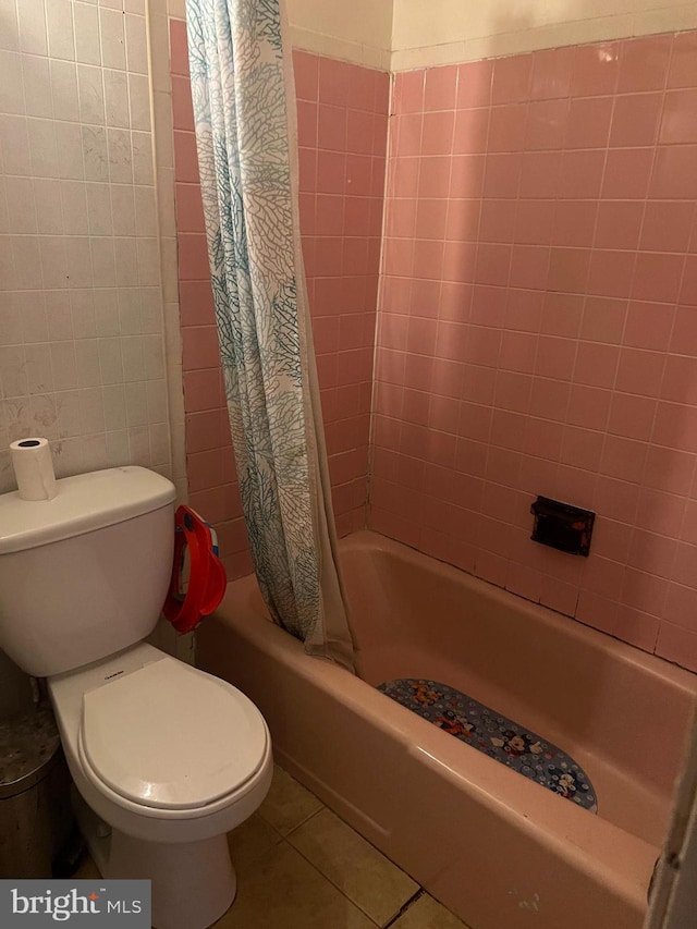 bathroom featuring tile patterned flooring, tile walls, shower / tub combo, and toilet