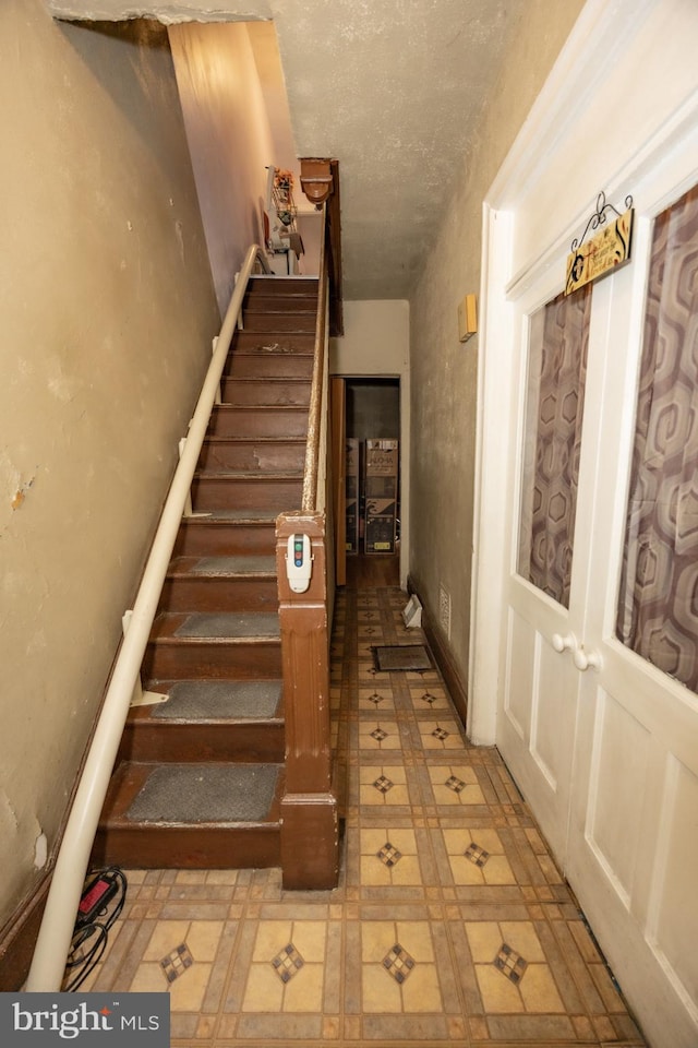 staircase with a textured ceiling