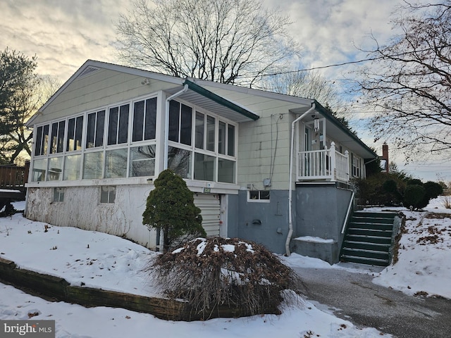 snow covered property with a sunroom