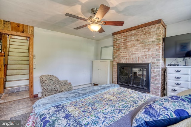 bedroom with ceiling fan, a brick fireplace, and a baseboard heating unit