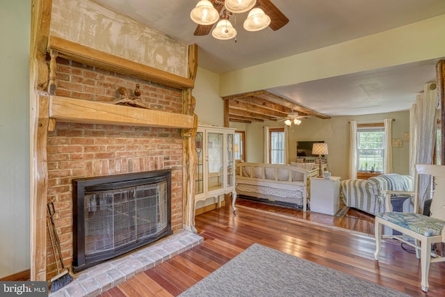 living room with ceiling fan, wood-type flooring, and a brick fireplace