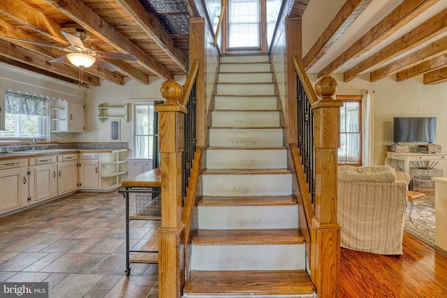 stairs with ceiling fan, sink, and beam ceiling