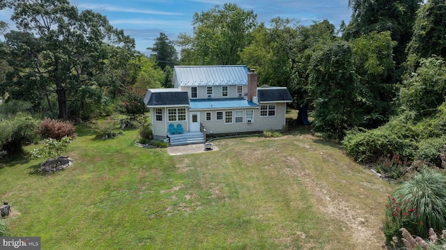 rear view of property featuring a fire pit and a lawn