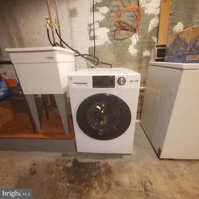 clothes washing area featuring washer / clothes dryer and sink