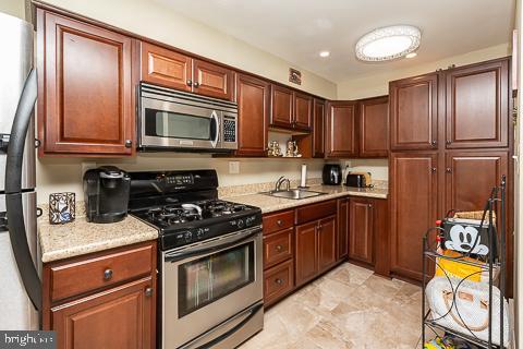 kitchen with sink, light stone countertops, and appliances with stainless steel finishes