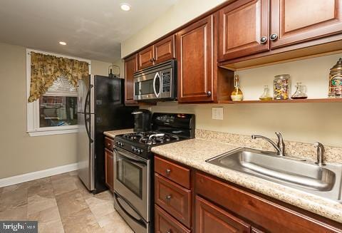 kitchen with sink, light stone countertops, and appliances with stainless steel finishes