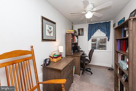 carpeted office space with ceiling fan