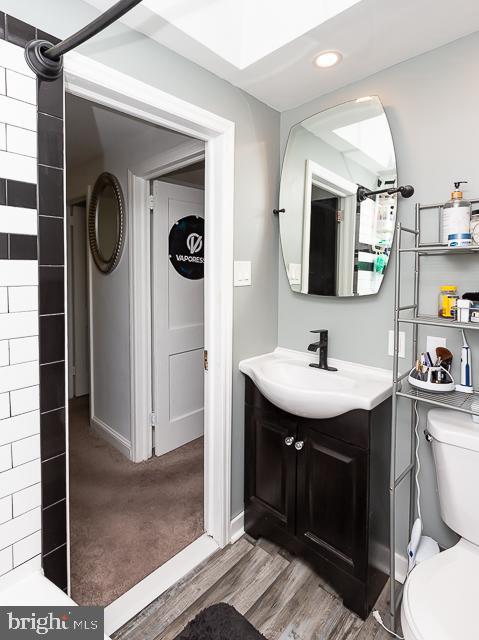 bathroom featuring vanity, wood-type flooring, and toilet