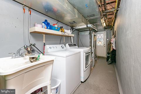 clothes washing area with washing machine and clothes dryer and sink